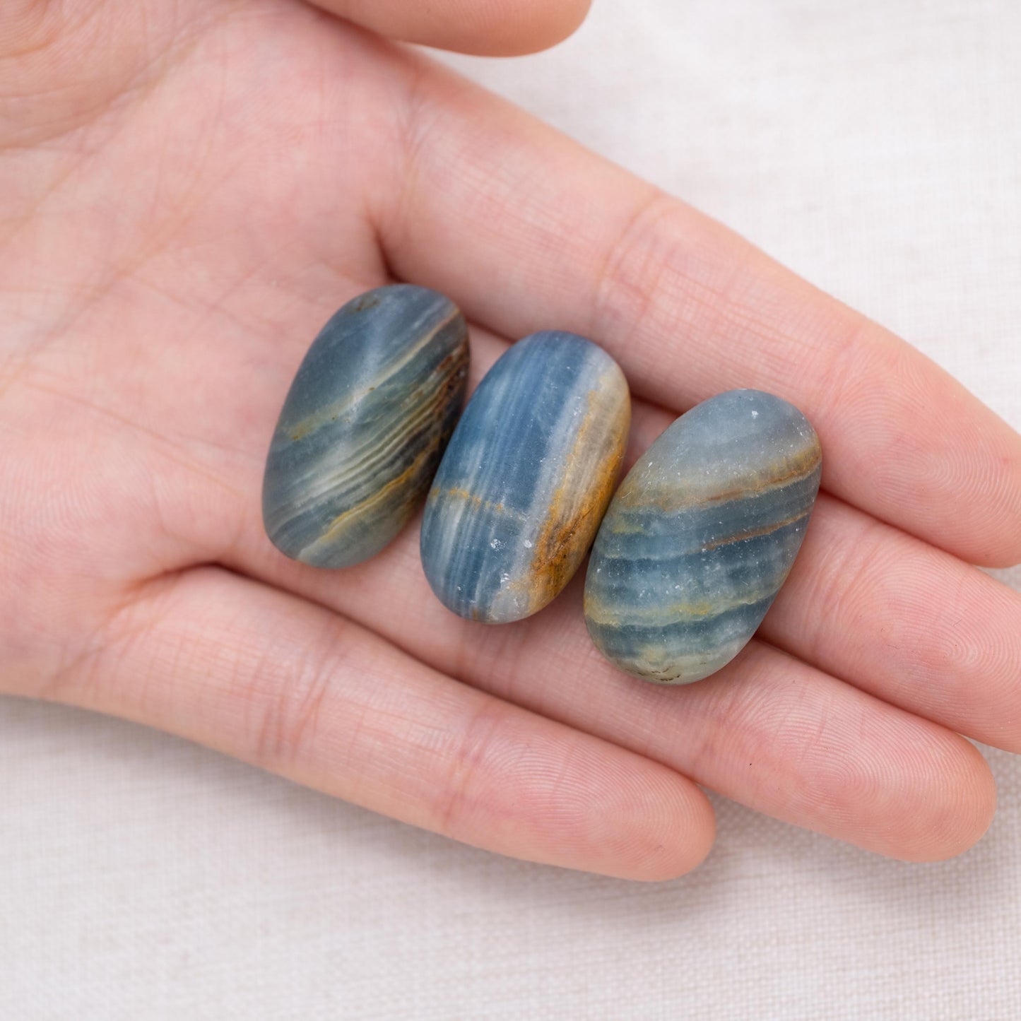 Hand holding Blue Onyx tumbled stone for strength and stability