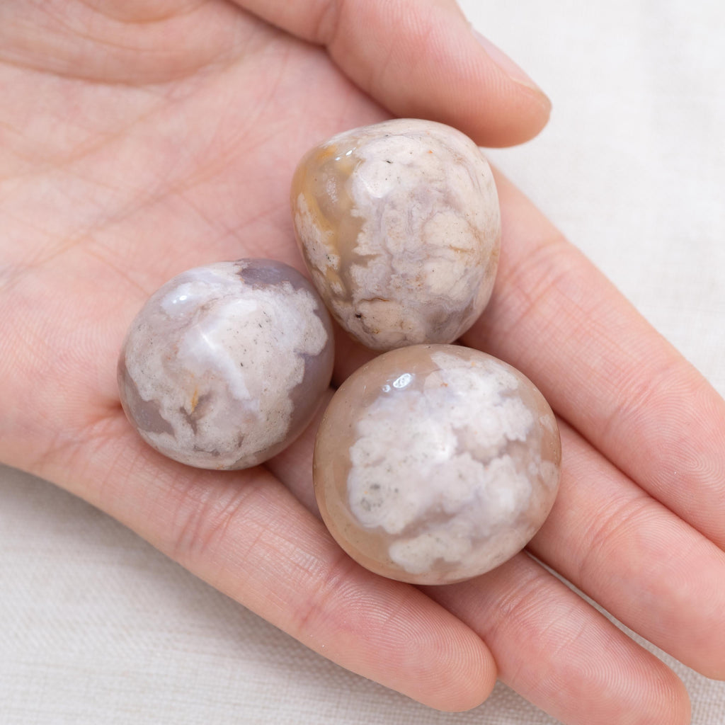 Hand holding Flower Agate tumbled stone for growth and joy