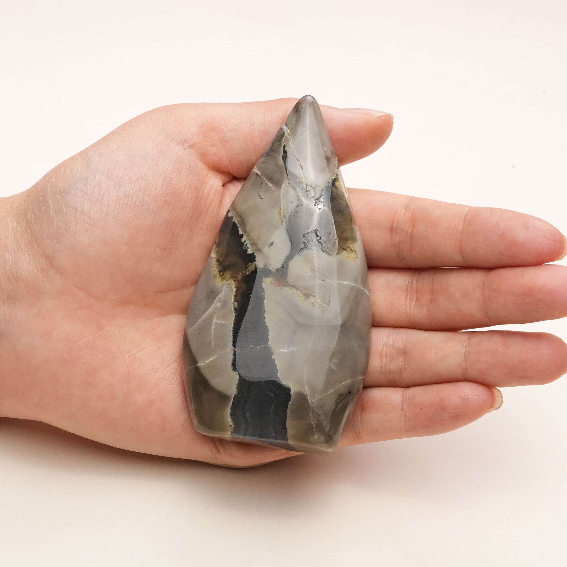 Hand holding a Volcanic Agate Freeform Crystal to show scale and the crystal's smooth, polished surface